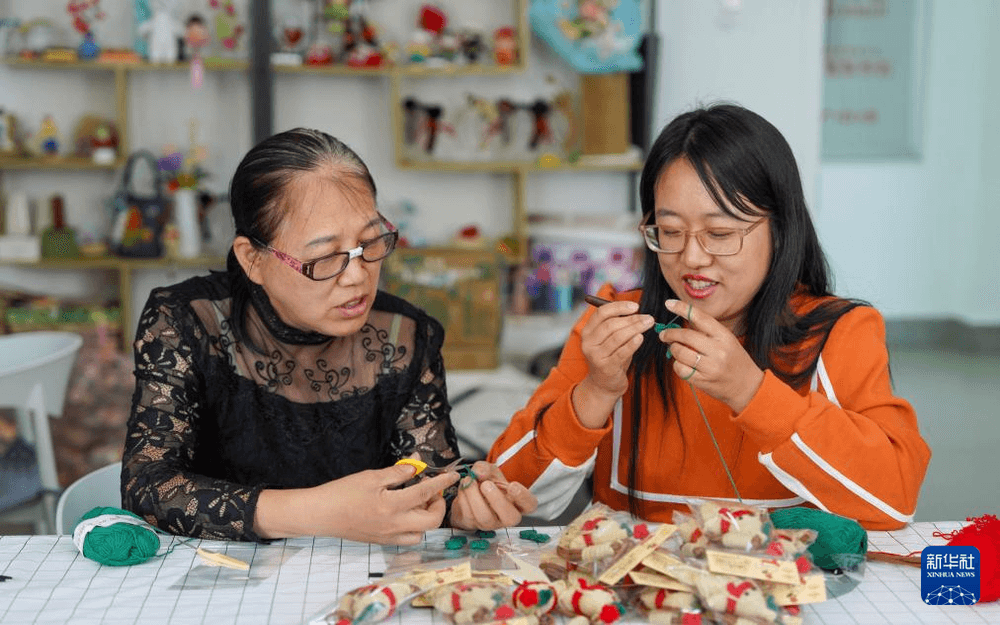 两名手艺人在“春巧巧”妇女手工项目传承实践基地交流